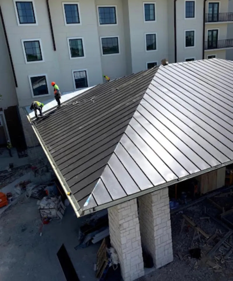 Crew installing standing seam metal roof panels on a commercial project in Stratford